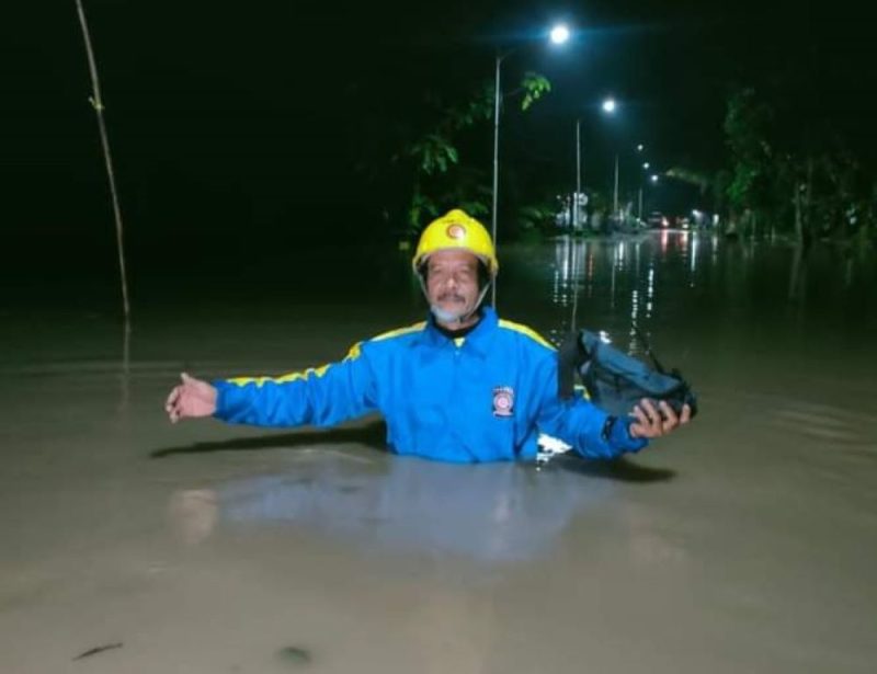 Seorang petugas Taruna Siaga Bencana sedang berjalan di antara genangan air yang menutup jalan di wilayah Kecamatan Pilangkenceng, Kabupaten Madiun, Jawa Timur. Foto: Ist