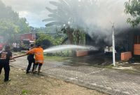 Petugas Pemadam Kebakaran sedang melakukan penyiraman ke mobil Datsun Go yang terbakar saat diparkir di garasi rumah di Ngawi, Kamis (18/4/2024). Foto: Neumedia.id/Fatihah