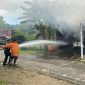 Petugas Pemadam Kebakaran sedang melakukan penyiraman ke mobil Datsun Go yang terbakar saat diparkir di garasi rumah di Ngawi, Kamis (18/4/2024). Foto: Neumedia.id/Fatihah