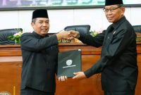 Pj. Bupati Madiun Tontro Pahlwanto (kiri) dan Wakil Ketua DPRD Kabupaten Madiun Slamet Rijadi menunjukkan bukti kesepakatan dalam sidang paripurna, Rabu (7/8/2024).